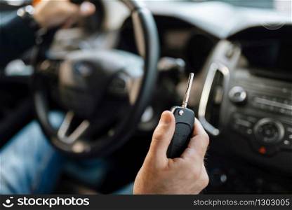 Male person behind the wheel of new automobile in car dealership. Buyer in vehicle showroom, man buying transport, auto dealer business. Male person behind the wheel of new automobile