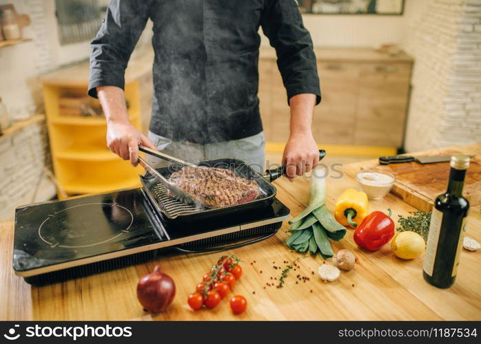 Male person cooking meat in a pan on the kitchen. Man preparing boiled pork on table electric stove