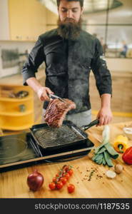 Male person cooking meat in a pan on the kitchen. Man preparing boiled pork. Male person cooking meat in a pan on the kitchen