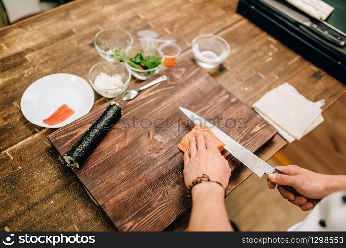 Male person cooking seafood on wooden table, asian food preparation process. Traditional japanese cuisine, sushi ingredients. Male person cooking seafood, asian food