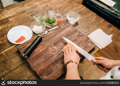 Male person cooking seafood on wooden table, asian food preparation process. Traditional japanese cuisine, sushi ingredients. Male person cooking seafood, asian food
