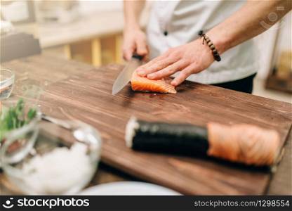 Male person cooking seafood on wooden table, asian food preparation process. Traditional japanese cuisine, sushi ingredients