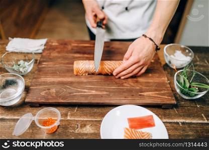 Male person cooking seafood on wooden table, japanese food preparation process. Traditional asian cuisine, sushi making