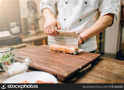 Male person cooking seafood on wooden table, japanese kitchen preparation process. Traditional asian cuisine, sushi making. Male person cooking seafood, japanese kitchen