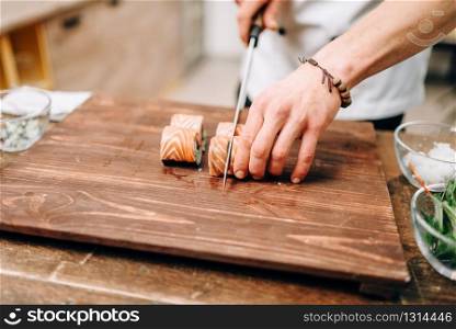 Male person cooking sushi on wooden table, japanese food preparation process. Traditional asian cuisine, seafood delicious