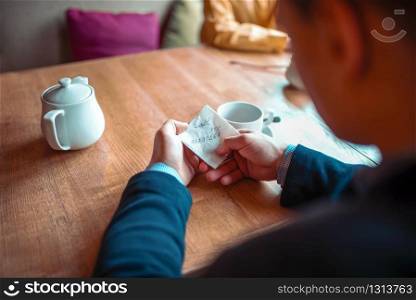 Male person hands holds love note with a phone number closeup view. Attractive proposal