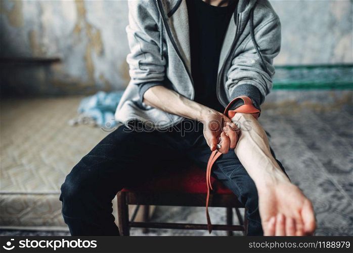 Male person with a syringe doing an injection dose in the arm. Narcotic addiction concept, drug addicted people. Male person doing an injection dose in the arm