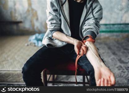 Male person with a syringe doing an injection dose in the arm. Narcotic addiction concept, drug addicted people. Male person doing an injection dose in the arm