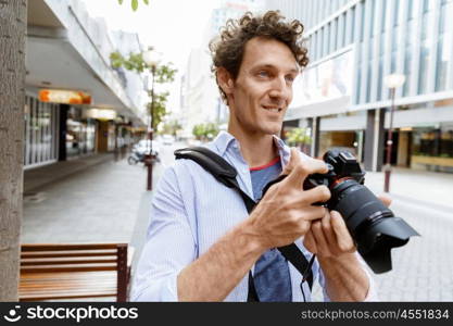 Male photographer taking picture. Professional photographer taking picture in city