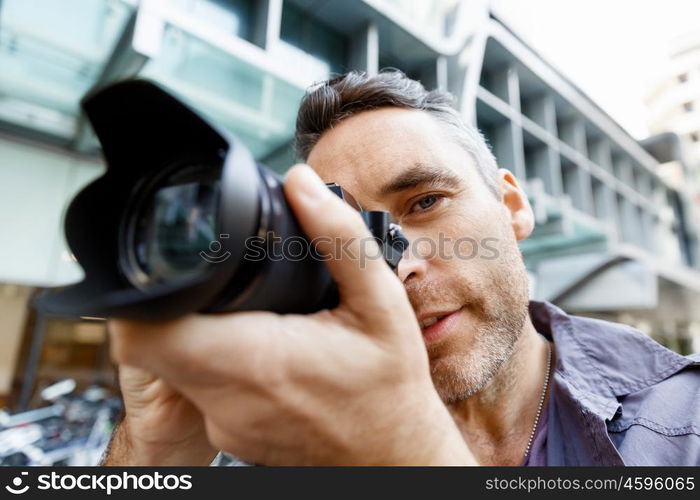 Male photographer taking picture. Professional photographer taking picture in city