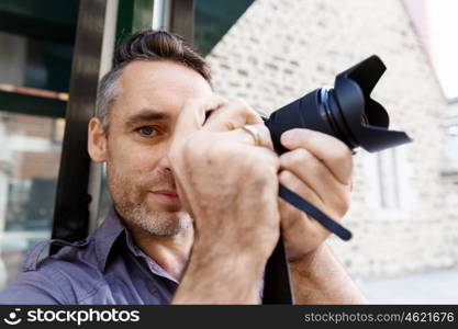 Male photographer taking picture. Professional photographer taking picture in city