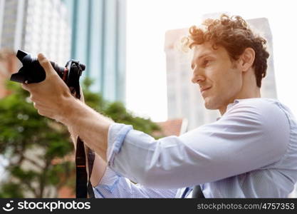 Male photographer taking picture. Professional photographer taking picture in city