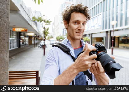 Male photographer taking picture. Professional photographer taking picture in city