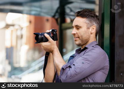 Male photographer taking picture. Professional photographer taking picture in city