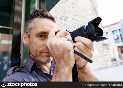 Male photographer taking picture. Professional photographer taking picture in city