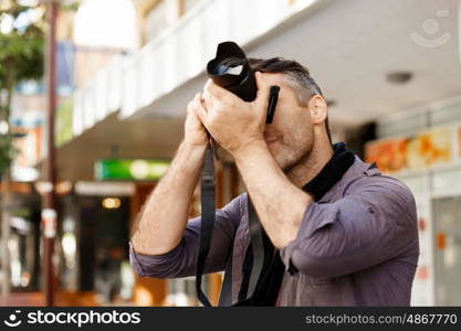 Male photographer taking picture. Professional photographer taking picture in city