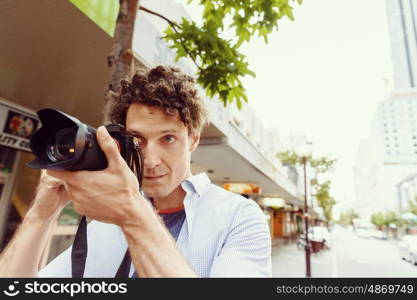 Male photographer taking picture. Professional photographer taking picture in city