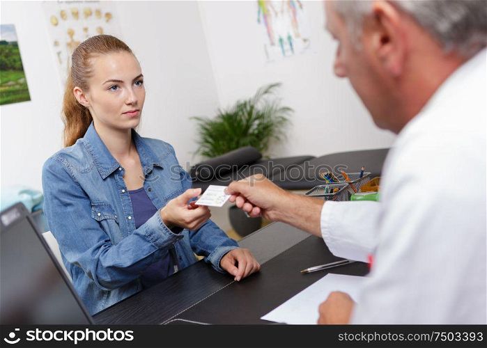male physician giving white blank calling card to female patient