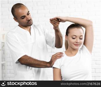 male physiotherapist checking woman s arm flexibility