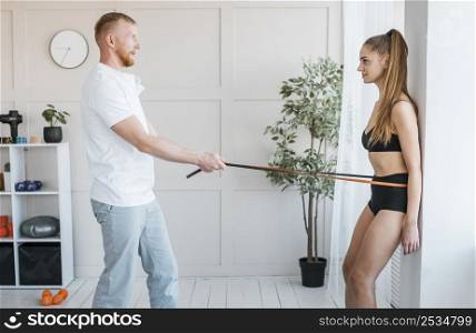 male physiotherapist doing elastic cord exercises with woman