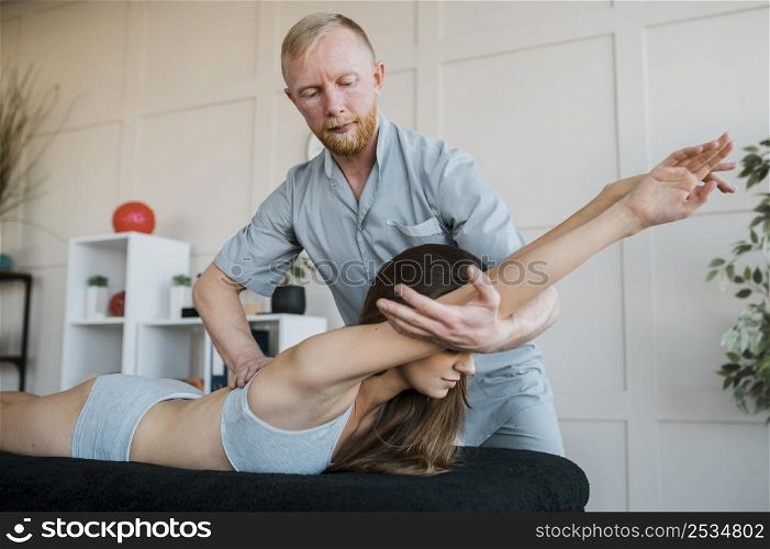 male physiotherapist doing treatment exercises with woman