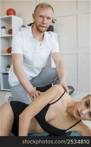 male physiotherapist helping female patient with treatment