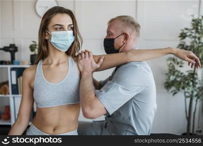 male physiotherapist wearing medical mask during therapy session