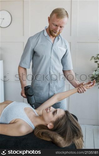 male physiotherapist with female patient equipment during physical therapy session