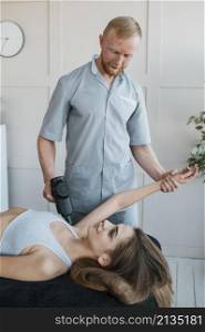male physiotherapist with female patient equipment during physical therapy session
