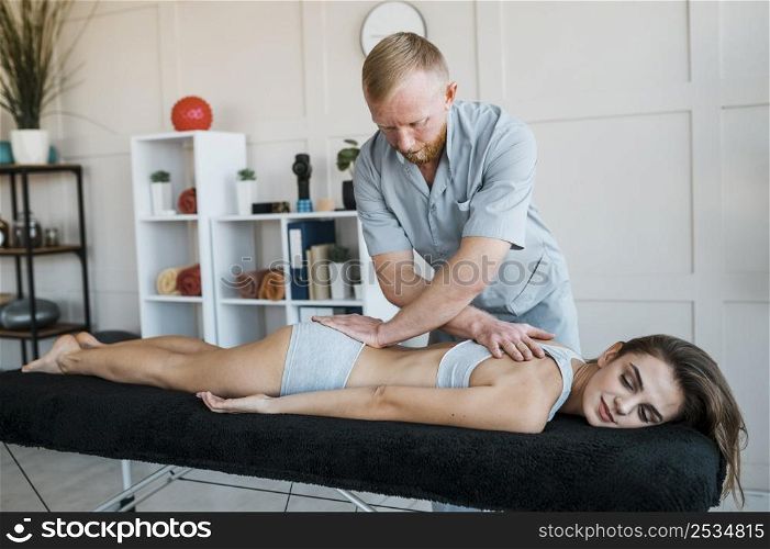 male physiotherapist woman during session physical therapy