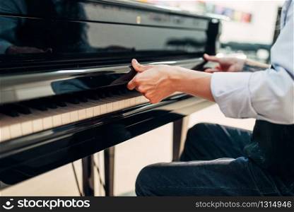 Male pianist opens the keyboard lid of the black grand piano. Musician prepares to performance on the royale. Pianist opens the keyboard lid of grand piano