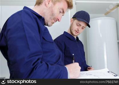 male plumber and apprentice working on boiler