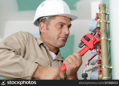 male plumber fixing water meter with adjustable wrench