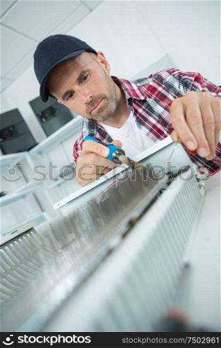 male plumber repairing radiator with a soldering iron