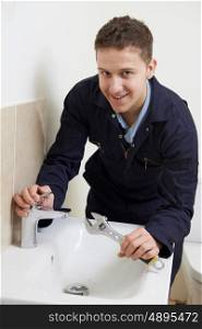 Male Plumber Working On Sink Using Wrench