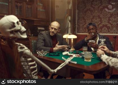 Male poker players and skeleton at gaming table with green cloth, fun, casino. Games of chance addiction, risk, gambling house. Men leisures with whiskey and cigars. Poker players and skeleton at gaming table, fun