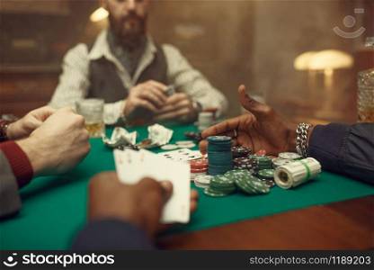 Male poker players at gaming table with green cloth, casino. Games of chance addiction, risk, gambling house. Men leisures with whiskey and cigars. Male poker players at gaming table, casino