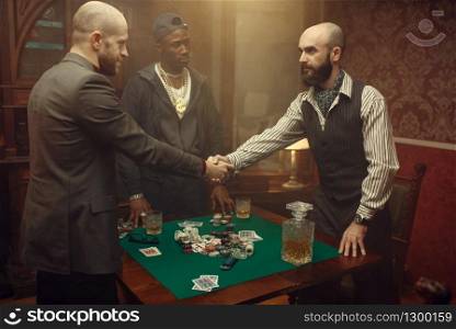 Male poker players shake hands in casino. Games of chance addiction, risk, gambling house. Men leisures with whiskey and cigars. Male poker players shake hands in casino