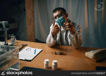 Male psychiatrist in mask and glasses sitting at the table, mental hospital. Doctor in clinic for the mentally ill