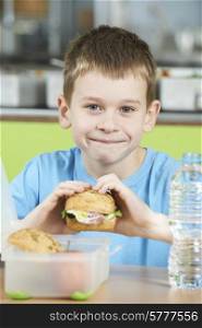Male Pupil Sitting At Table In School Cafeteria Eating Healthy Packed Lunch