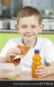 Male Pupil Sitting At Table In School Cafeteria Eating Unhealthy Packed Lunch