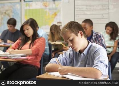 Male Pupil Studying At Desk In Classroom