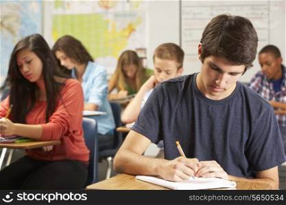 Male Pupil Studying At Desk In Classroom