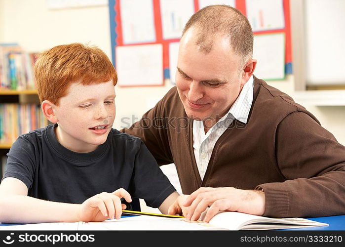 Male Pupil Studying in classroom with teacher