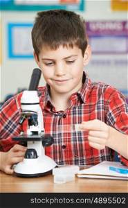 Male Pupil Using Microscope In Science Lesson