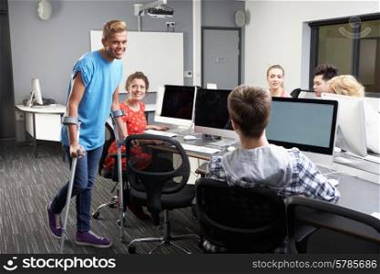 Male Pupil Walking On Crutches In Computer Class