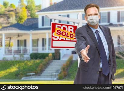 Male Real Estate Agent Reaching for Hand Shake Wearing Medical Face Mask with Sold For Sale Sign Behind.