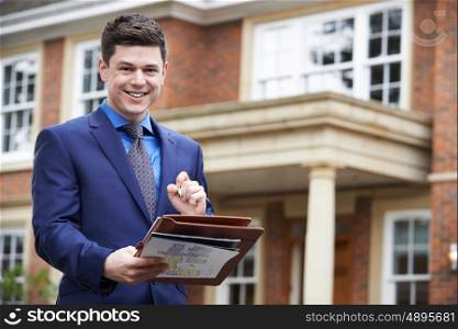 Male Realtor Standing Outside Residential Property