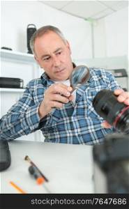 male repairing an camera at his workplace on white background