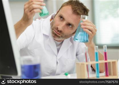 male researcher holding flask with blue liquid in the lab
